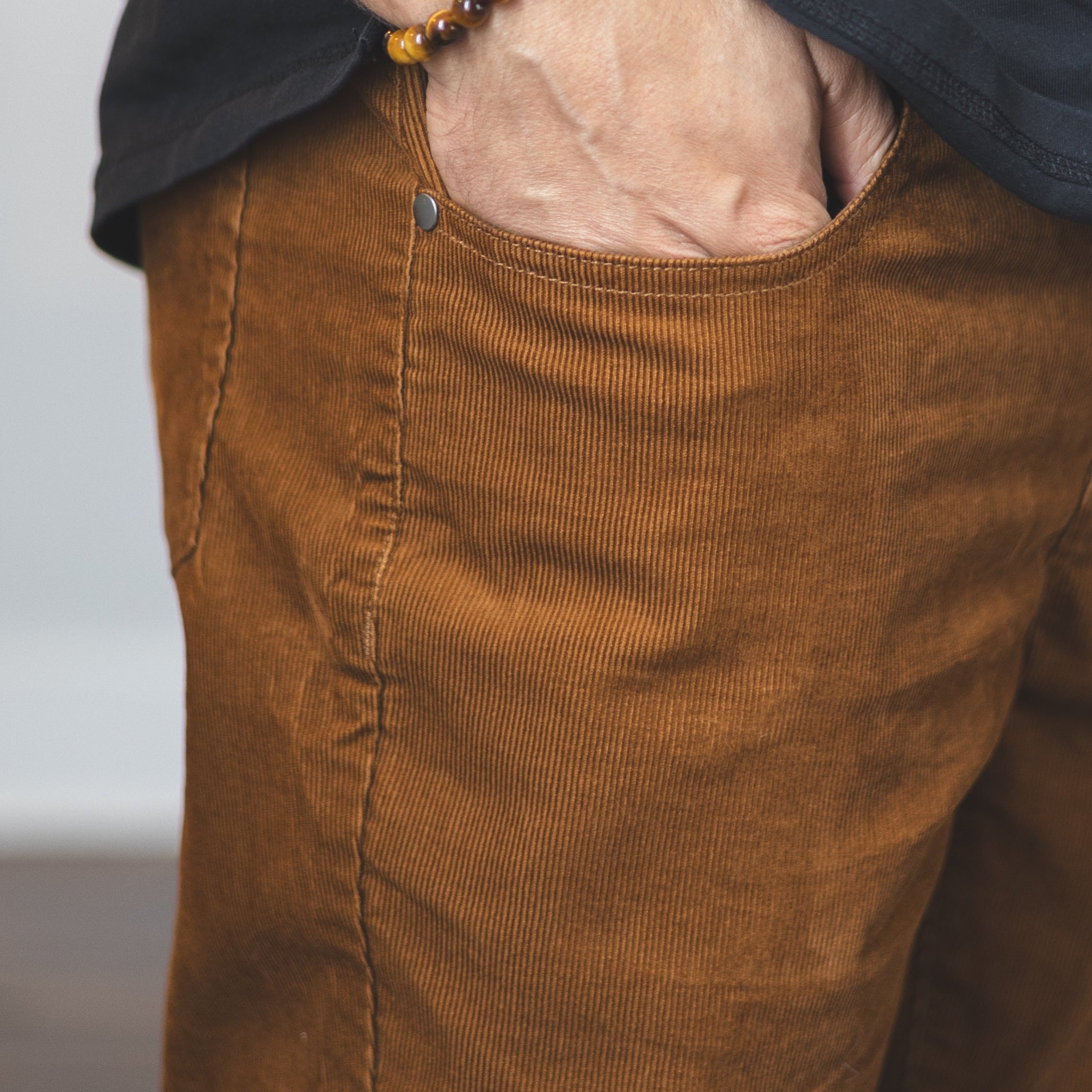 Person wearing brown pants and a black shirt with a blurred background