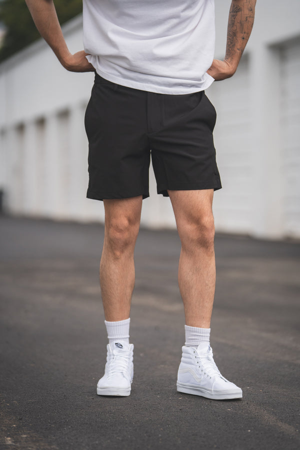 Person wearing black shorts and white sneakers on a blurred background