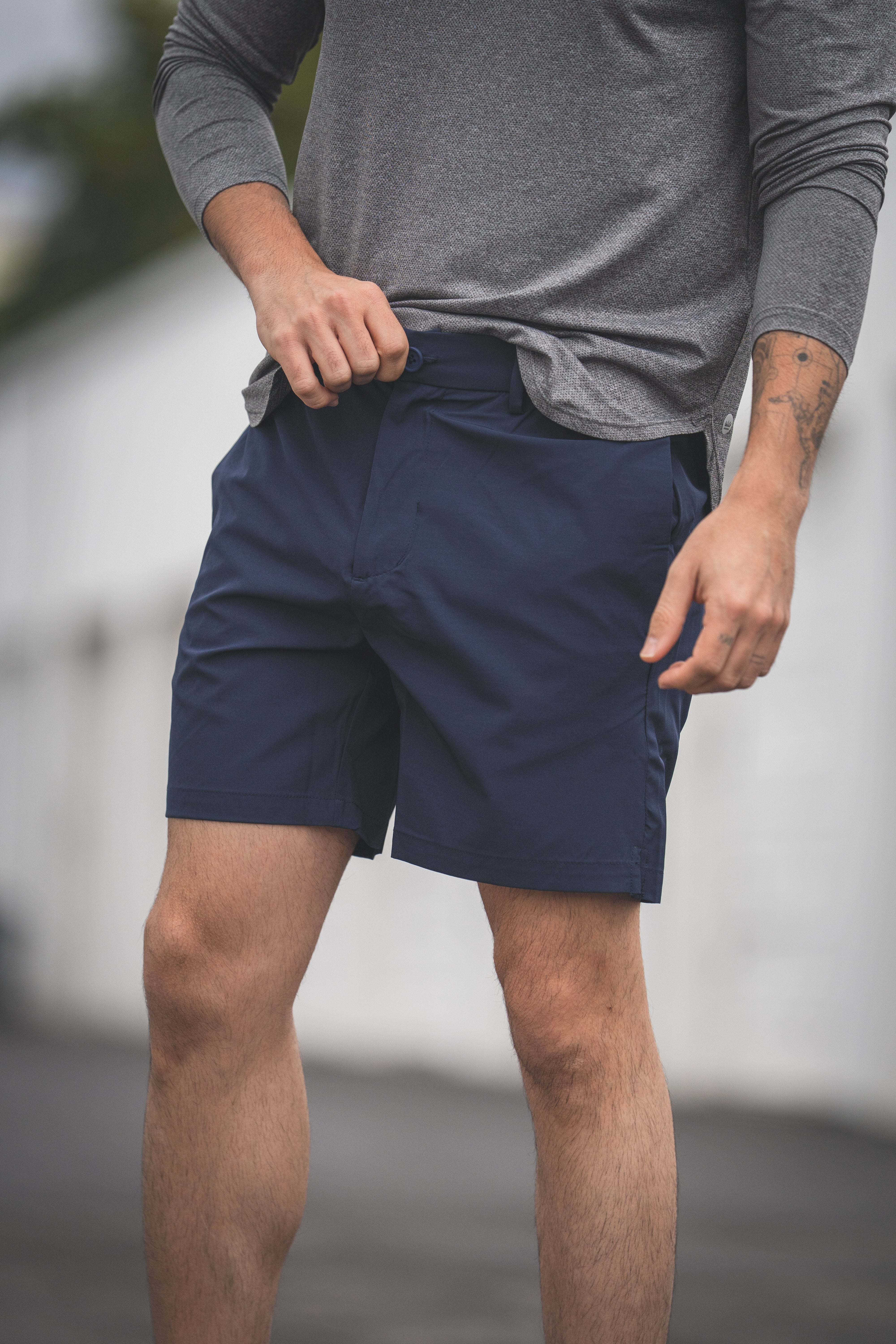 Person wearing navy shorts and a gray long-sleeve shirt outdoors